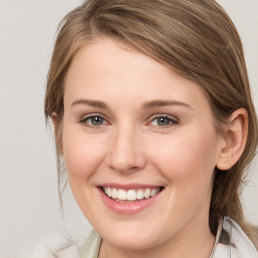 Joyful white young-adult female with medium  brown hair and grey eyes