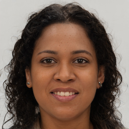 Joyful black young-adult female with long  brown hair and brown eyes