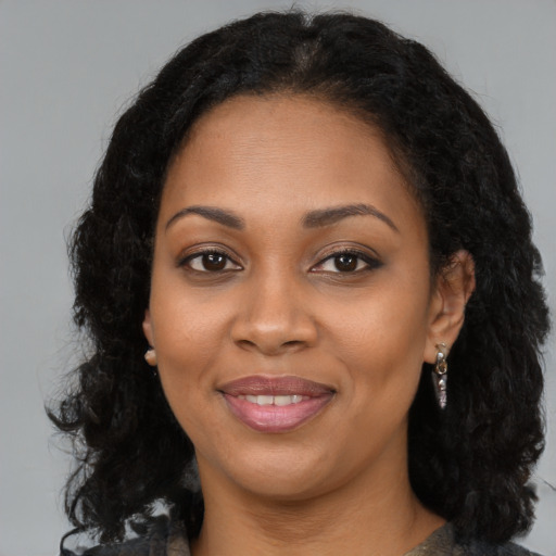 Joyful black young-adult female with long  brown hair and brown eyes