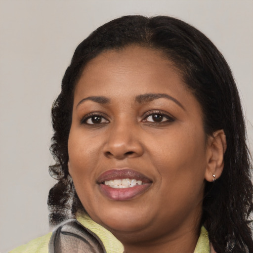 Joyful black young-adult female with long  brown hair and brown eyes
