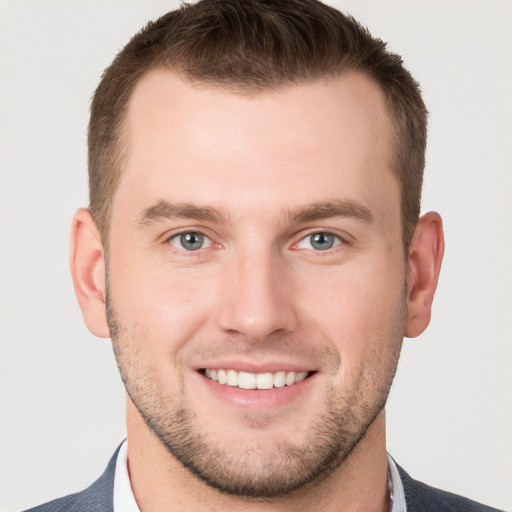 Joyful white young-adult male with short  brown hair and grey eyes