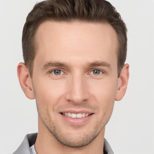 Joyful white young-adult male with short  brown hair and grey eyes