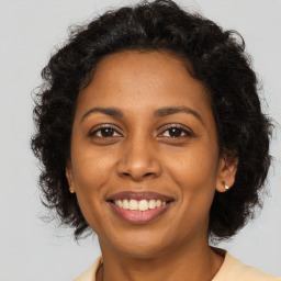 Joyful black adult female with long  brown hair and brown eyes