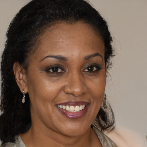 Joyful black adult female with long  brown hair and brown eyes