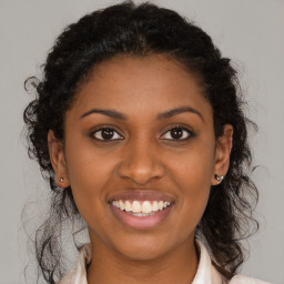 Joyful black young-adult female with long  brown hair and brown eyes