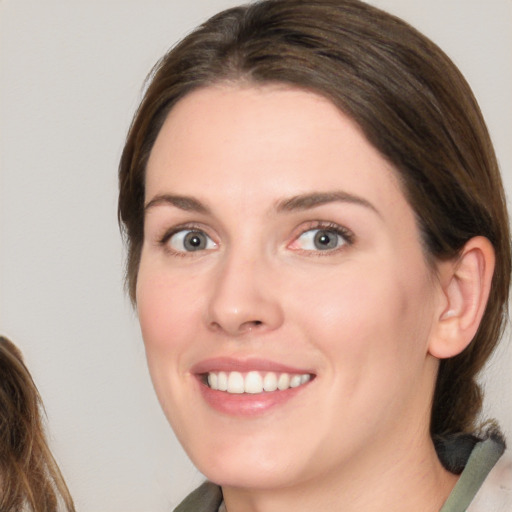 Joyful white young-adult female with medium  brown hair and green eyes