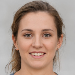 Joyful white young-adult female with medium  brown hair and grey eyes