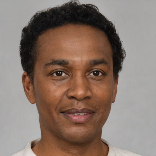 Joyful black adult male with short  black hair and brown eyes