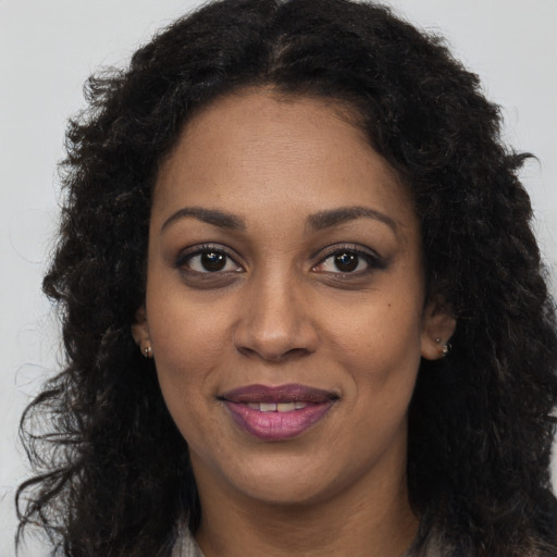 Joyful black young-adult female with long  brown hair and brown eyes