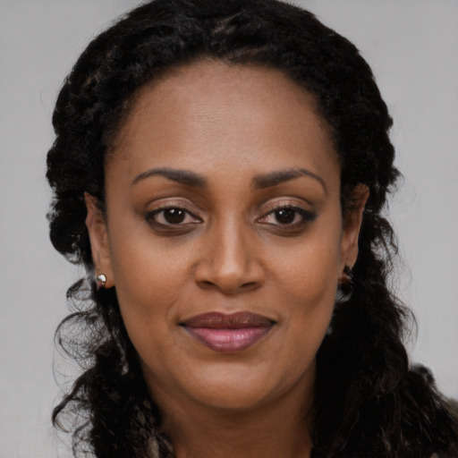 Joyful black young-adult female with long  black hair and brown eyes