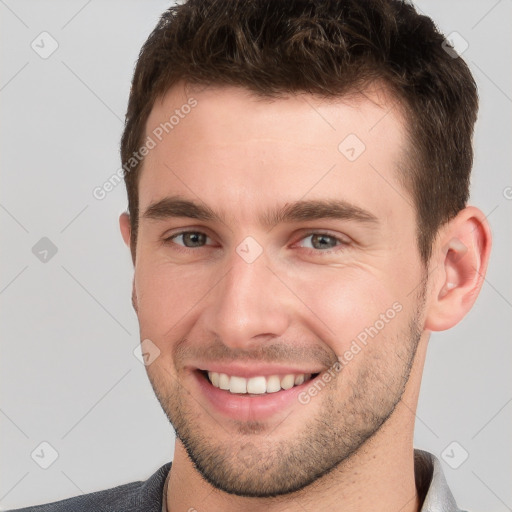 Joyful white young-adult male with short  brown hair and grey eyes