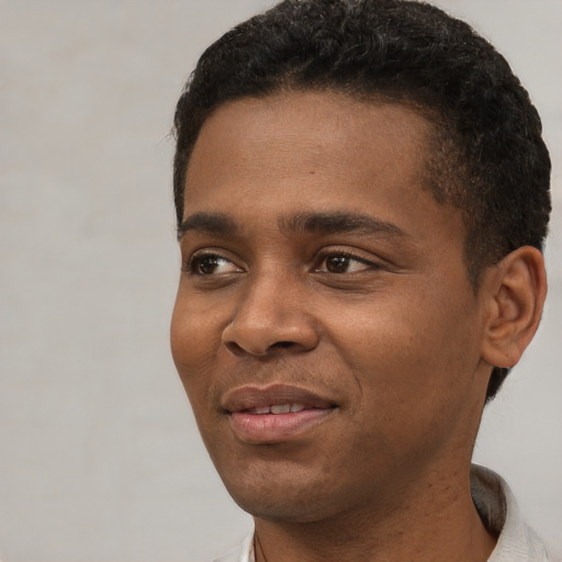 Joyful black young-adult male with short  black hair and brown eyes