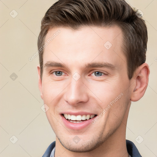 Joyful white young-adult male with short  brown hair and grey eyes