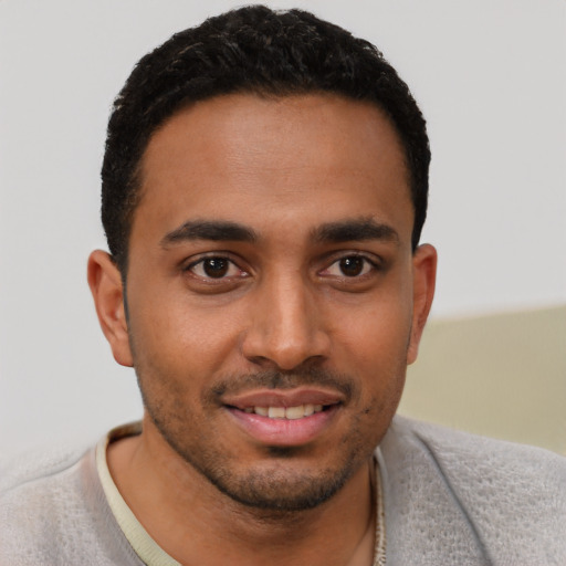 Joyful black young-adult male with short  black hair and brown eyes