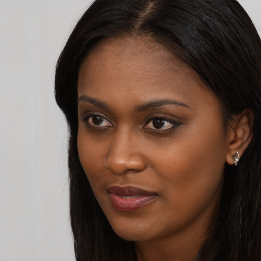 Joyful black young-adult female with long  brown hair and brown eyes