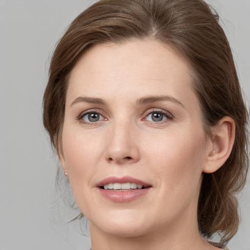 Joyful white young-adult female with medium  brown hair and grey eyes