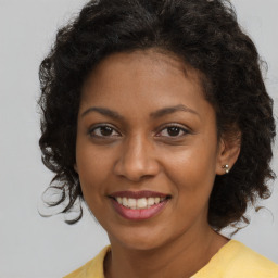 Joyful black young-adult female with long  brown hair and brown eyes