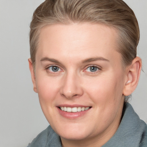 Joyful white young-adult female with short  brown hair and blue eyes