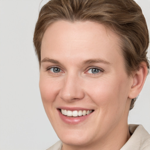 Joyful white young-adult female with short  brown hair and grey eyes