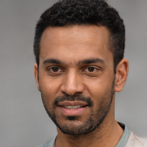 Joyful black young-adult male with short  black hair and brown eyes