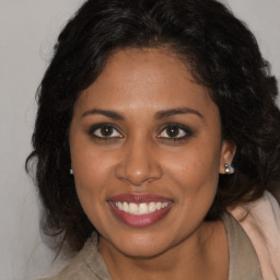 Joyful black young-adult female with long  brown hair and brown eyes