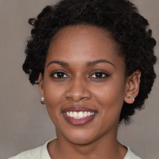 Joyful black young-adult female with short  brown hair and brown eyes
