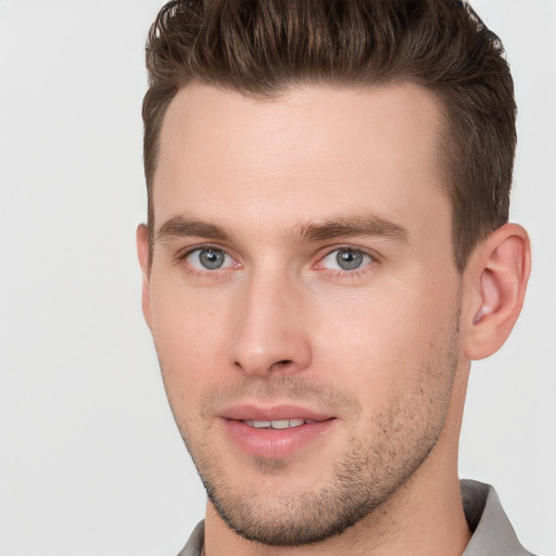 Joyful white young-adult male with short  brown hair and grey eyes