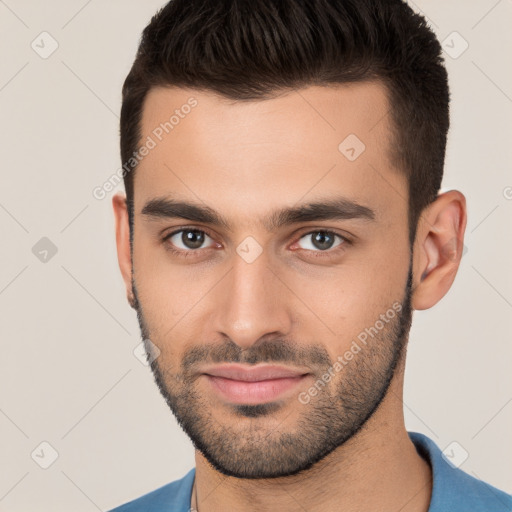 Joyful white young-adult male with short  black hair and brown eyes