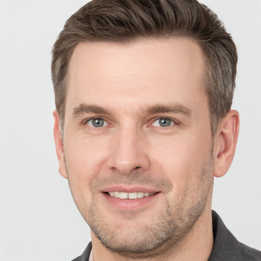 Joyful white young-adult male with short  brown hair and grey eyes