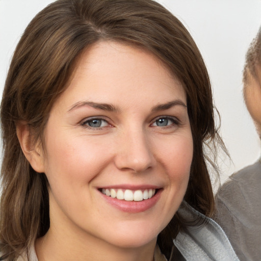 Joyful white young-adult female with medium  brown hair and grey eyes