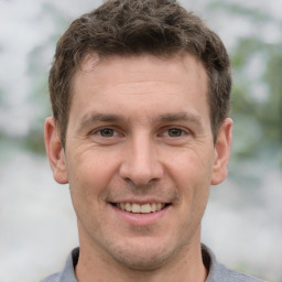 Joyful white adult male with short  brown hair and grey eyes