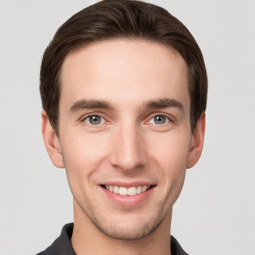 Joyful white young-adult male with short  brown hair and grey eyes