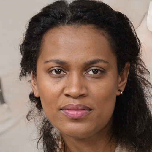 Joyful black adult female with long  brown hair and brown eyes