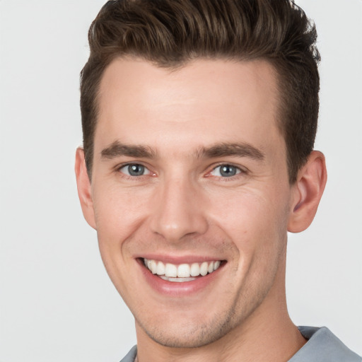 Joyful white young-adult male with short  brown hair and grey eyes