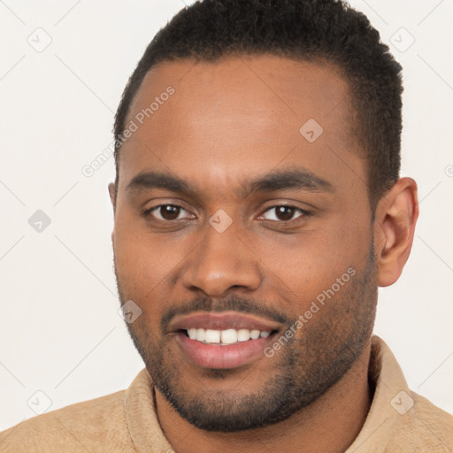 Joyful black young-adult male with short  brown hair and brown eyes