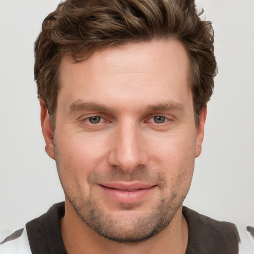 Joyful white young-adult male with short  brown hair and grey eyes