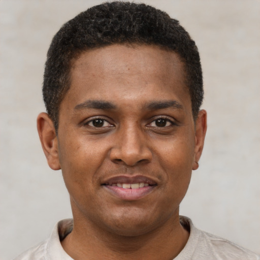 Joyful black young-adult male with short  brown hair and brown eyes