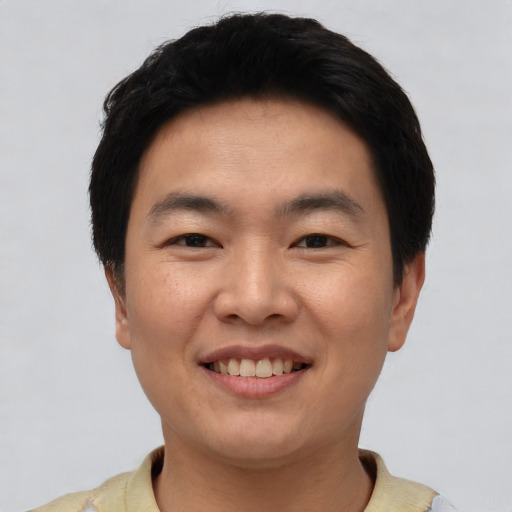 Joyful asian young-adult male with short  black hair and brown eyes