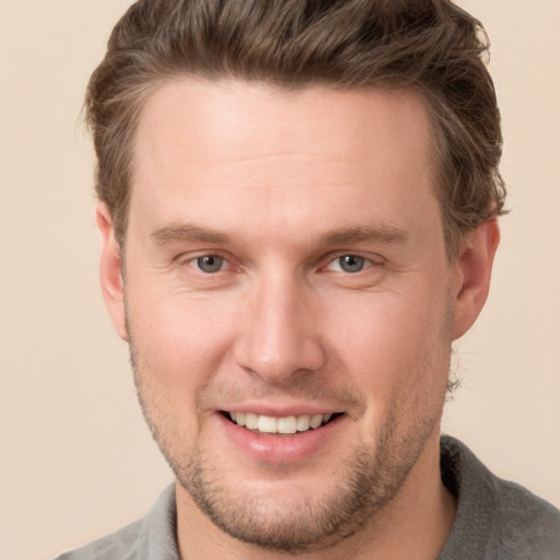 Joyful white young-adult male with short  brown hair and grey eyes