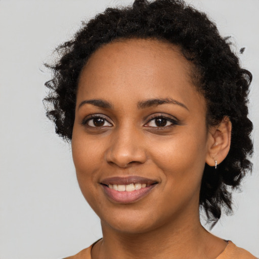 Joyful black young-adult female with long  black hair and brown eyes