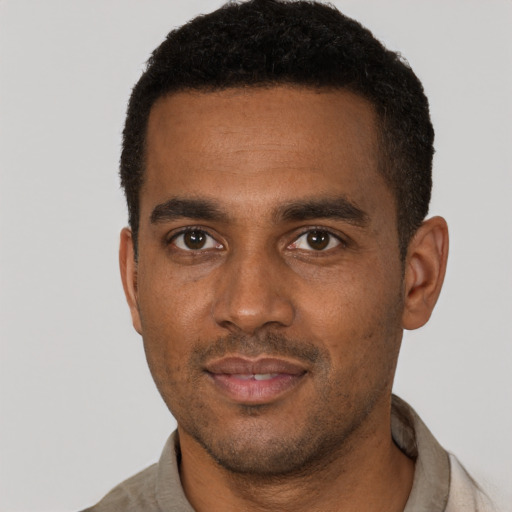 Joyful black young-adult male with short  brown hair and brown eyes