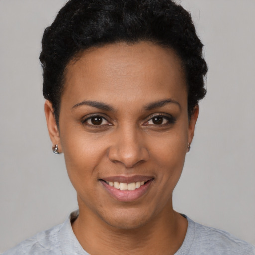 Joyful black young-adult female with short  black hair and brown eyes