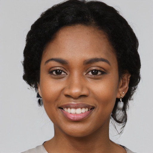 Joyful black young-adult female with long  black hair and brown eyes