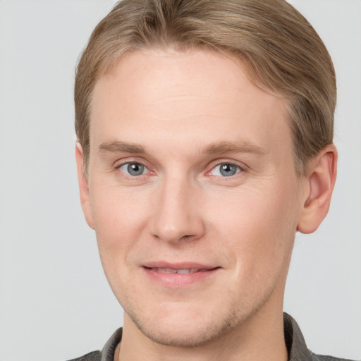 Joyful white young-adult male with short  brown hair and grey eyes