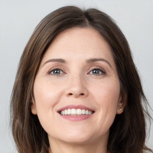 Joyful white young-adult female with long  brown hair and grey eyes