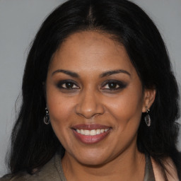 Joyful black young-adult female with long  brown hair and brown eyes