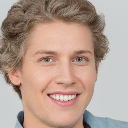 Joyful white young-adult male with short  brown hair and blue eyes