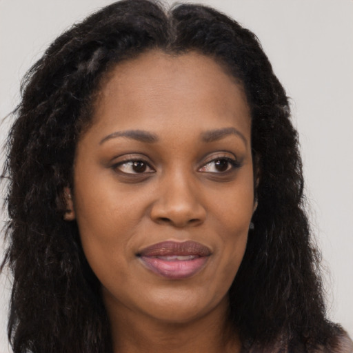 Joyful black young-adult female with long  brown hair and brown eyes