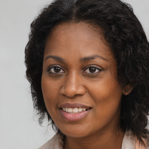 Joyful black young-adult female with long  brown hair and brown eyes