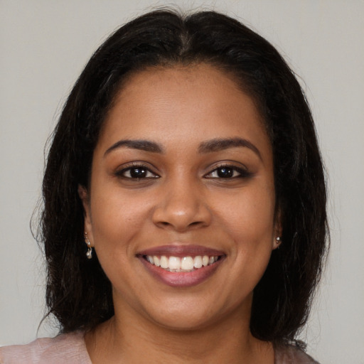 Joyful black young-adult female with long  brown hair and brown eyes